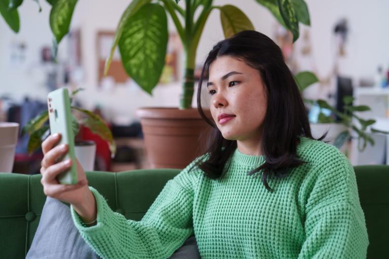 Vrouw in groene trui met smartphone