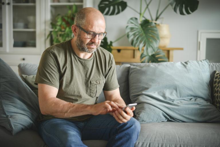 Man zit thuis op de bank met smartphone